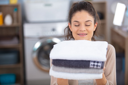 beautiful young woman is holding a pile of clean towelsの写真素材