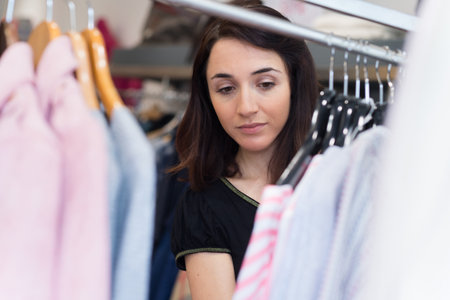 store assistant sorting clothes on stores railsの写真素材