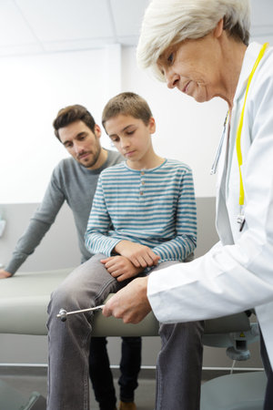 female doctor examining little boy with father support