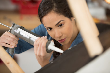 woman applying adhesive product to chair baseの写真素材