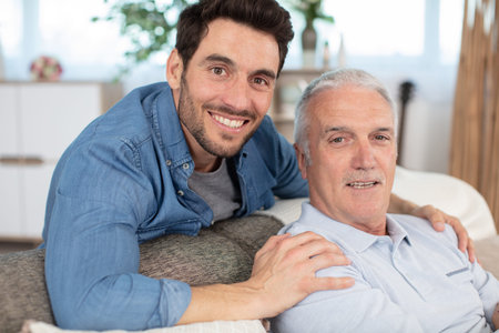 happy elderly father and son sit on couch