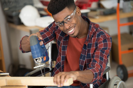 a man carpenter cuts a wooden beam using a jigsawの写真素材