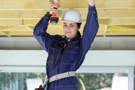 female contractor using a cordless drill on roof timbersの写真素材