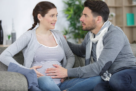 pregnant woman suffering belly ache and husband comfortingの写真素材