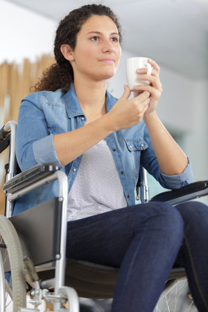 beautiful happy woman in wheelchair drinking coffee