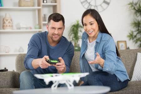 young couple playing with a small quadrocopter drone at home