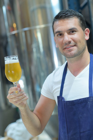 side view of blonde man looking at dark craft beerの写真素材