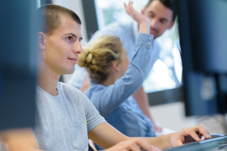 student raising a hand to ask question in computer class