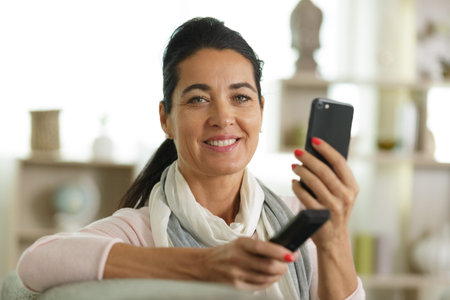 woman hand holding remote control and smartphone