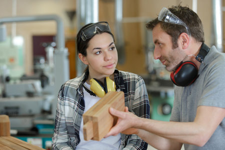professional teacher showing carpentry machinery to studentの写真素材