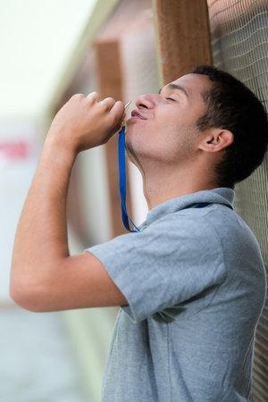 man in sportswear kissing gold medalの写真素材