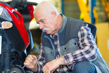 senior motorcycle mechanic working at his workshopの写真素材
