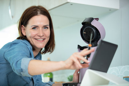 happy woman repairing broken coffee machineの写真素材