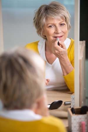 portrait of senior female doing her lipstickの写真素材