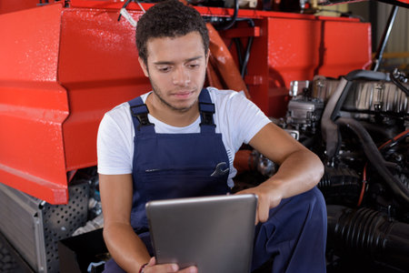 young firetruck mechanic consulting the laptopの写真素材
