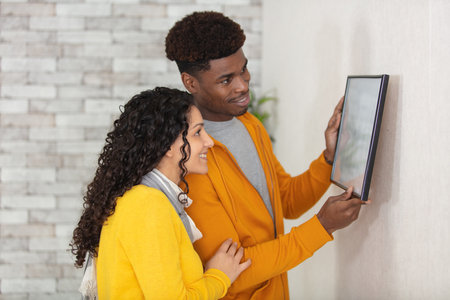 attractive young couple hanging a picture frameの写真素材