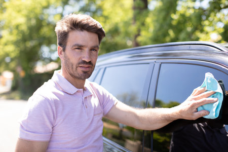 young man cleaning his car outdoorsの写真素材