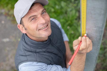 man uses a tape measure a piece of metalの写真素材