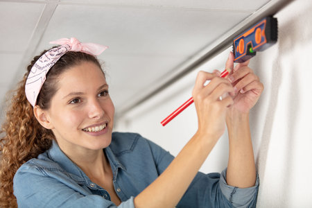 mature woman using a spirit level and marking the wall