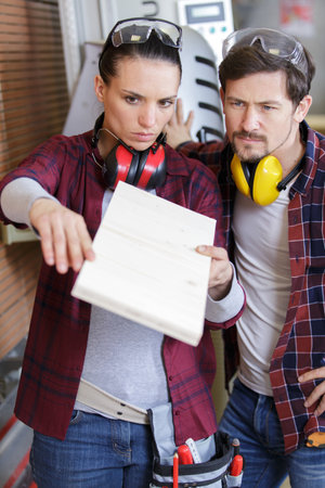 male and female carpenters in discussion in workshopの写真素材