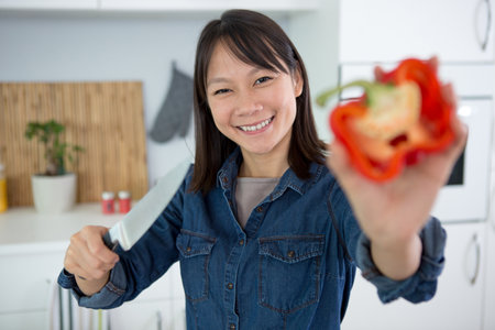 happy woman holding a pepper close to the cameraの写真素材