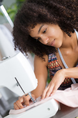 young female fashion designer working on sewing machineの写真素材