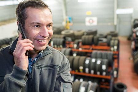 tire shop worker using his phoneの写真素材