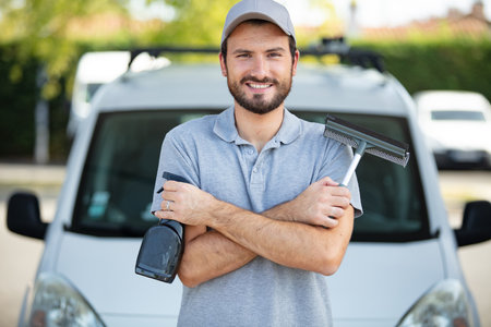 happy male cleaner in blue uniform standing with vacuum cleanerの写真素材