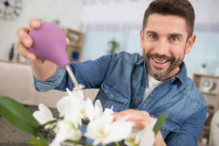 smiling man watering his flowersの写真素材