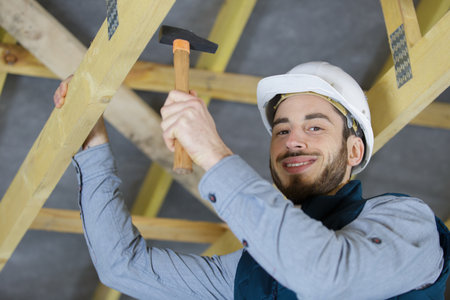 happy roofermaker using a hammer in traditional constructionの写真素材