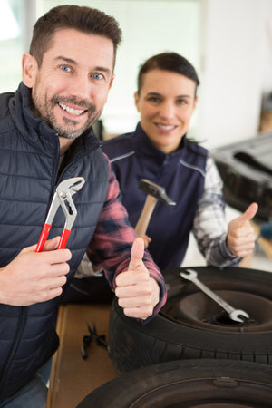 tire mechanics showing ok gesture and holding toolsの写真素材