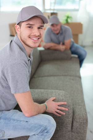 movers placing sofa on hardwood floor at homeの写真素材