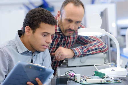 young male electrical engineering student observing microchipの写真素材