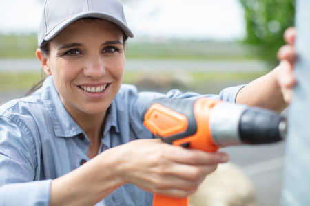 woman holding electric drill outdoors looking at the cameraの写真素材