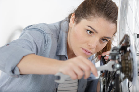 young woman repairing bicycle wheelの写真素材