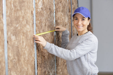 happy woman construction engineer making measurements on the wallの写真素材