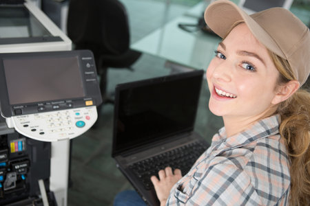 happy woman smiling at the camera fixing a printer
