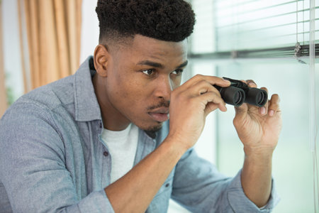 handsome man with binoculars on gray backgroundの写真素材