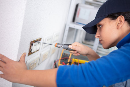 female electrician fixing socket to the wallの写真素材