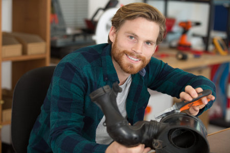 young male mechanic using long nosed pliers