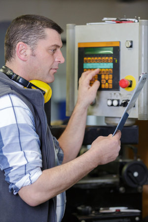 factory worker is programming a cnc milling machine