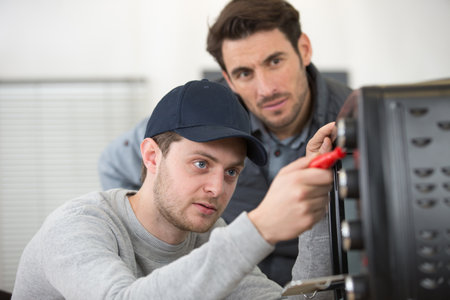 two men fixing oven in kitchenの写真素材