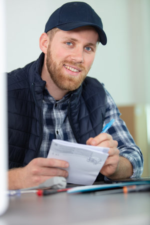 young male repairman checking appliance manualの写真素材