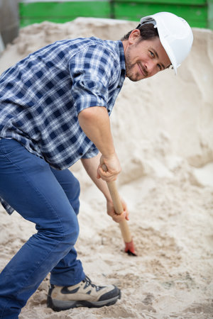 male manual worker shoveling sandの写真素材