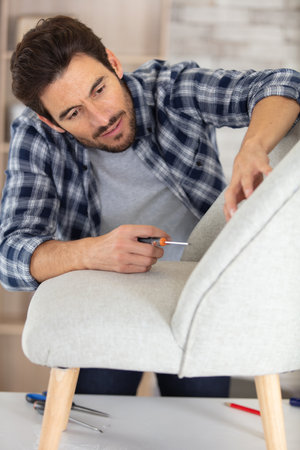 man repairing chair using a screwdriverの写真素材