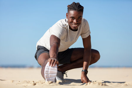 physically fit man doing stretching exercises on morning beach