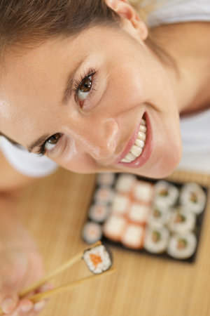 high angle view of woman holding sushi between chopsticksの写真素材