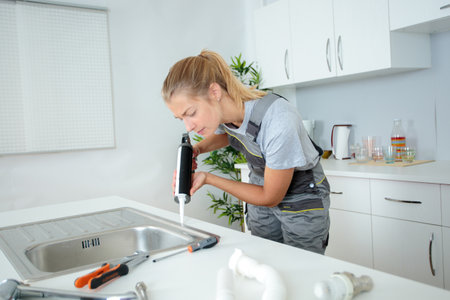 plumber is working with caulking gun and fixing the basinの写真素材