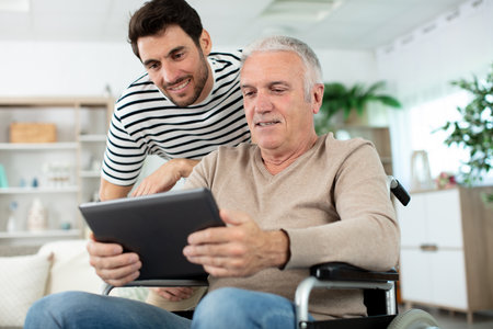 handsome man taking care about his eldery father in wheelchairの写真素材