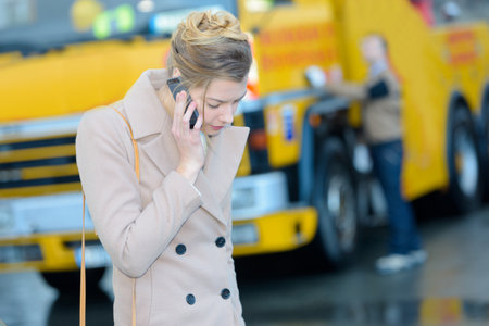 woman calling her insurance near tow truckの写真素材